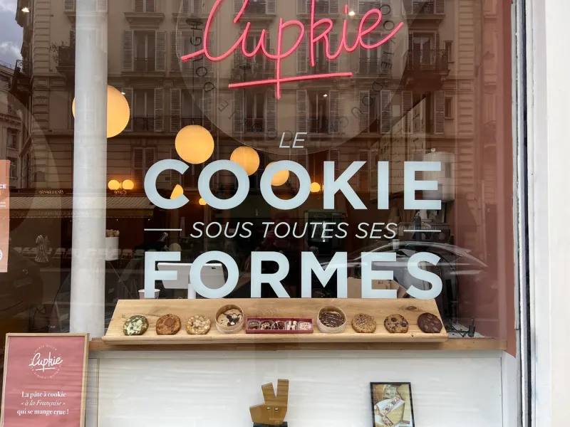 La vitrine Cupkie, 26 rue Monge, avec le néon rose et la vitrophanie « Le cookie sous toutes ses formes »
